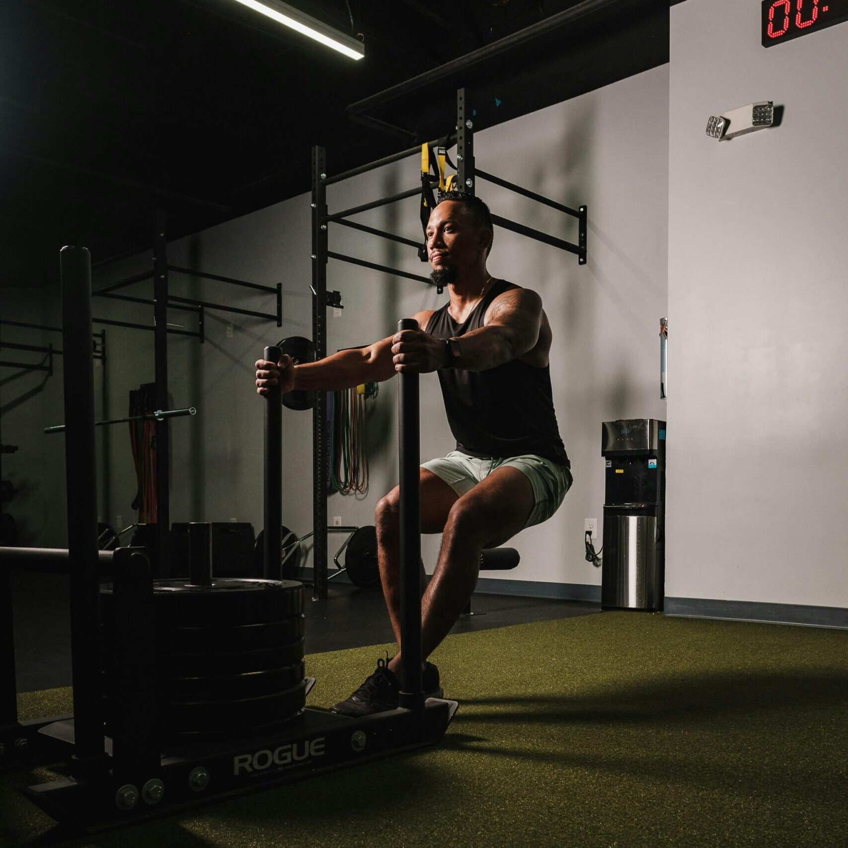 Focused man pushing weight sled in gym, demonstrating strength and endurance.