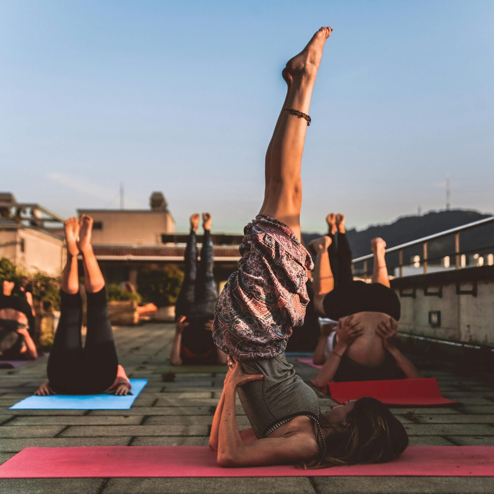 People practicing yoga on mats outdoors during sunset, focusing on wellness.